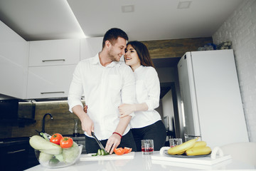 Lovely couple at home in a kithen. Woman and man prepare salad. Woman in a white shirt