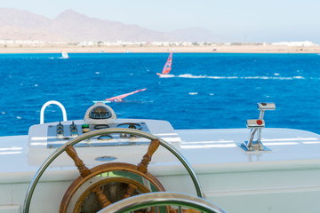 Yacht steering wheel on blue sky background. The yacht's steering wheel sails on the sea
