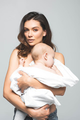 portrait of beautiful naked mother holding adorable baby boy, isolated on grey