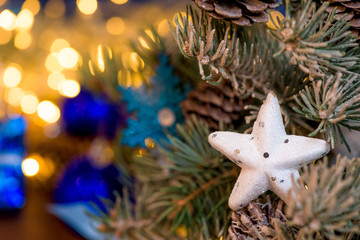 white star Christmas toy on a spruce branch, on a blue background. bokeh of lights. classic blue 2020. Christmas card background