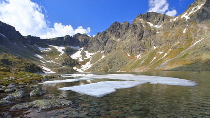 Mountain lake in spring with mighty rocky ridge in the background