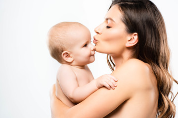 portrait of attractive naked mother hugging and kissing baby boy, isolated on white