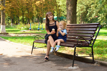 Mom and daughter eat ice cream on the bench