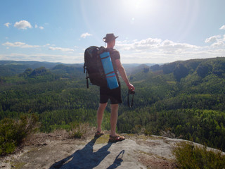 Traveler with backpack and camera in hands exploring nature.