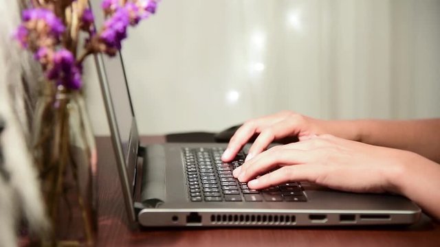 The hand of a woman typing the keyboard of a notebook