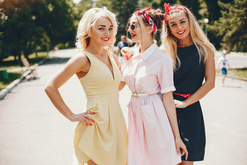 Stylish girls in a retro dress. Vintage ladies in a summer park. Three women have fun