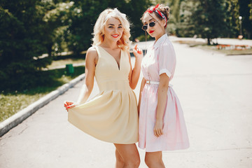 Stylish girls in a retro dress. Vintage ladies in a summer park. Two women have fun