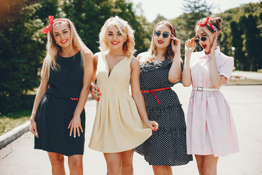 Stylish girls in a retro dress. Vintage ladies in a summer park. Four women have fun