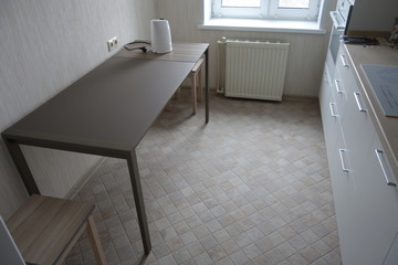 Interior of kitchen with table in pale and white with rough tiled floors