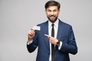 studio photo of young handsome businessman wearing suit holding business card