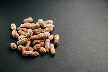 Fototapeta na wymiar Nuts on a black background. Peanuts in a shell in a slide.