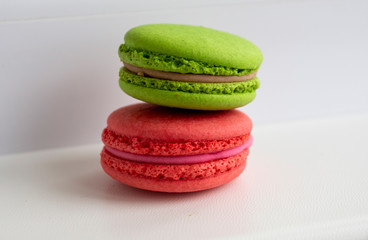 Two macaroons stacked on white background one is pink the other one is lime greenher one 