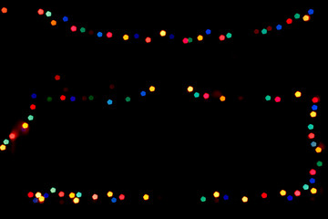 Street festive illumination glittering in darkness. Blurred holiday garland lighting for New Year. Natural background with pentagonal bokeh. Night photo with black copy space for text or logo.
