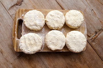 Russian traditional syrniki raw uncooked cottage cheese pancakes on old wooden background breakfast