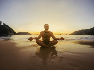 Fototapeta na wymiar Silhouette of man doing yoga exercises at sunset beach.