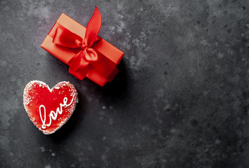 Cheesecake - a heart-shaped cake with the inscription love and a gift with a red ribbon for Valentine's Day on a stone background with copy space for your text