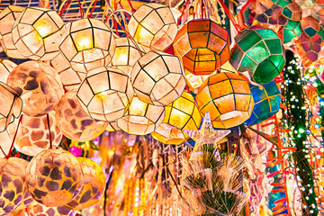 Brightly illuminated colorful traditional lanterns made of thin sea shells hanging outside a shop at Divisoria market in Manila, Philippines. - obrazy, fototapety, plakaty