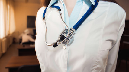 Closeup of woman in medical gown with stethoscope. - obrazy, fototapety, plakaty
