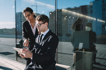 Coworking business people sharing tablet on street
Young black woman with man in glasses coworking and using tablet having discussion on street against glassy window of building