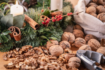 Close up view of whole walnuts, a nutcracker and scattered nuts and shells on a wooden table....