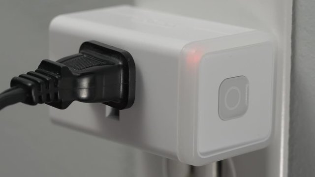 Connecting a WiFi smart plug into a house outlet to control an electrical device with the wireless network.