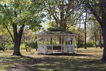 A empty white gazebo in the park on a autumn day.