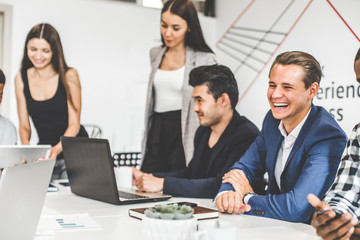 A team of young office workers, businessmen with laptop working at the table, communicating together in an office. Corporate businessteam and manager in a meeting. coworking.