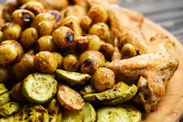 Grilled vegetables and chicken wings on the wooden plate