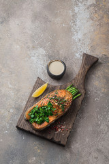 Fried salmon steak with asparagus on wooden board, copy space