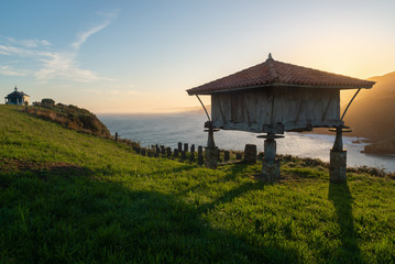 Typical granary (horreo) and the chapel of La Regalina in Cadavedo, Asturias, Spain	