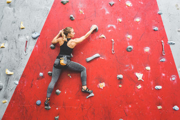 Sportswoman climber moving up on steep rock, climbing on artificial wall indoors. Extreme sports...