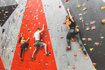 Athletes climber moving up on steep rock, climbing on artificial wall indoors. Extreme sports and...