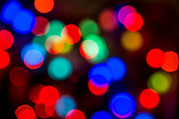 Christmas colorful bright background. Festive abstract bokeh, defocused large colored lights garland red and blue on a black background. Copy space