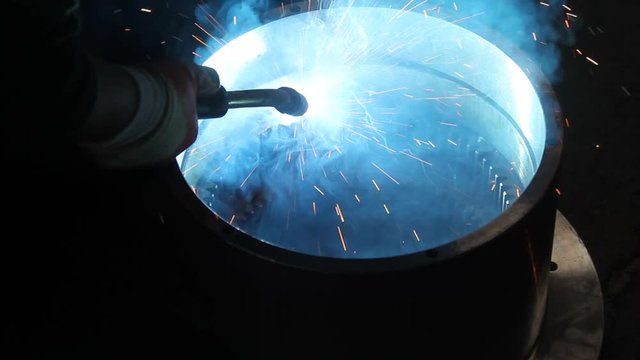 inside factory, welder with welding sparks