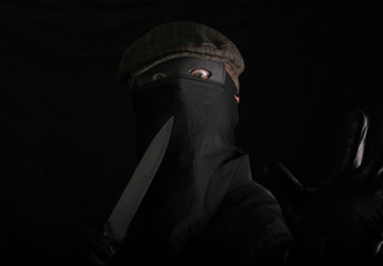 masked criminal with crazy holds a knife