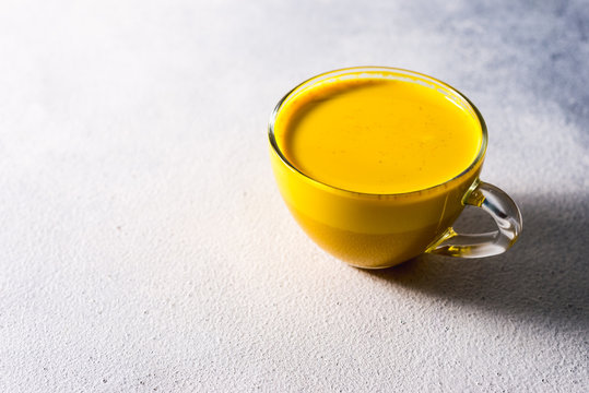 Golden turmeric milk on the white background with spices cinnamon and ingredients