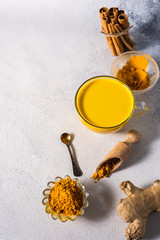 Golden turmeric milk on the white background with spices cinnamon and ingredients