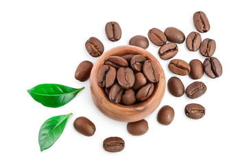 Heap of roasted coffee beans in wooden bowl with leaves isolated on white background. Top view. Flat lay.