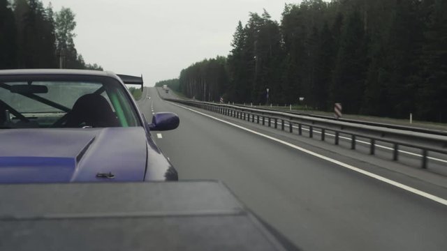Transportation of a sports car on a highway. View from a towing vehicle