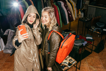Obraz premium Three women taking a selfie while shopping in a clothing store. They are happy and smiling at camera. Shopping concept, also related to social media addiction.