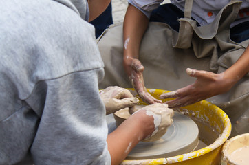 hands of teacher and student while learning pottery