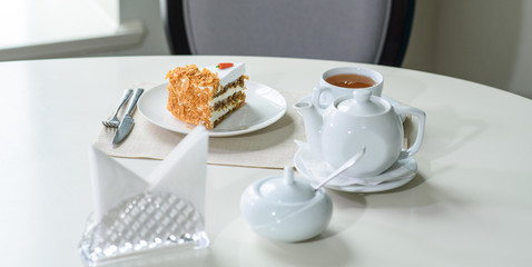 Delicious carrot cake and a cup of black tea on the table in a cozy coffee shop