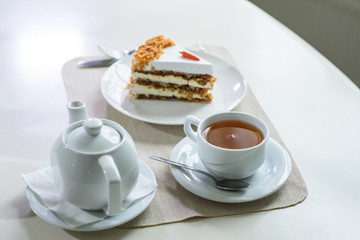 Delicious carrot cake and a cup of black tea on the table in a cozy coffee shop