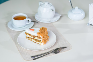Delicious carrot cake and a cup of black tea on the table in a cozy coffee shop