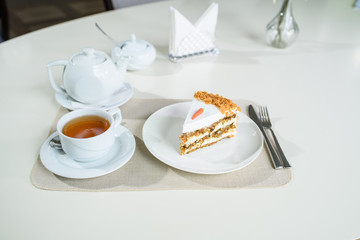 Delicious carrot cake and a cup of black tea on the table in a cozy coffee shop
