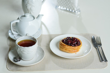 Danish with cherries and black tea on a table in a cozy coffee shop