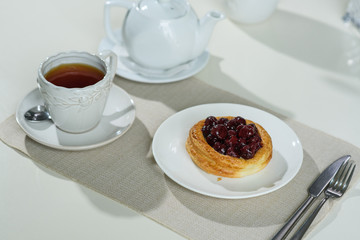 Danish with cherries and black tea on a table in a cozy coffee shop