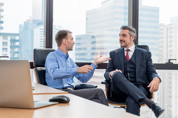 Young Caucasian worker sitting and discussion or explain about work with smiling Caucasian boss or CEO. in meeting room in office