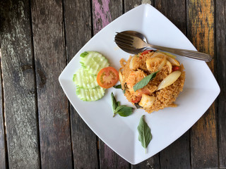 Fried rice with shrimp and vegetable in white plate on the on beautiful wooden table background from top view. Thai style food.