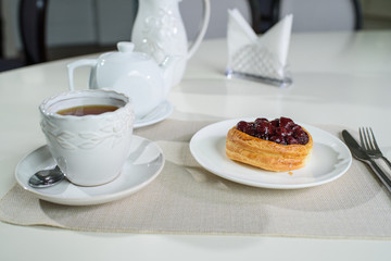 Danish with cherries and black tea on a table in a cozy coffee shop